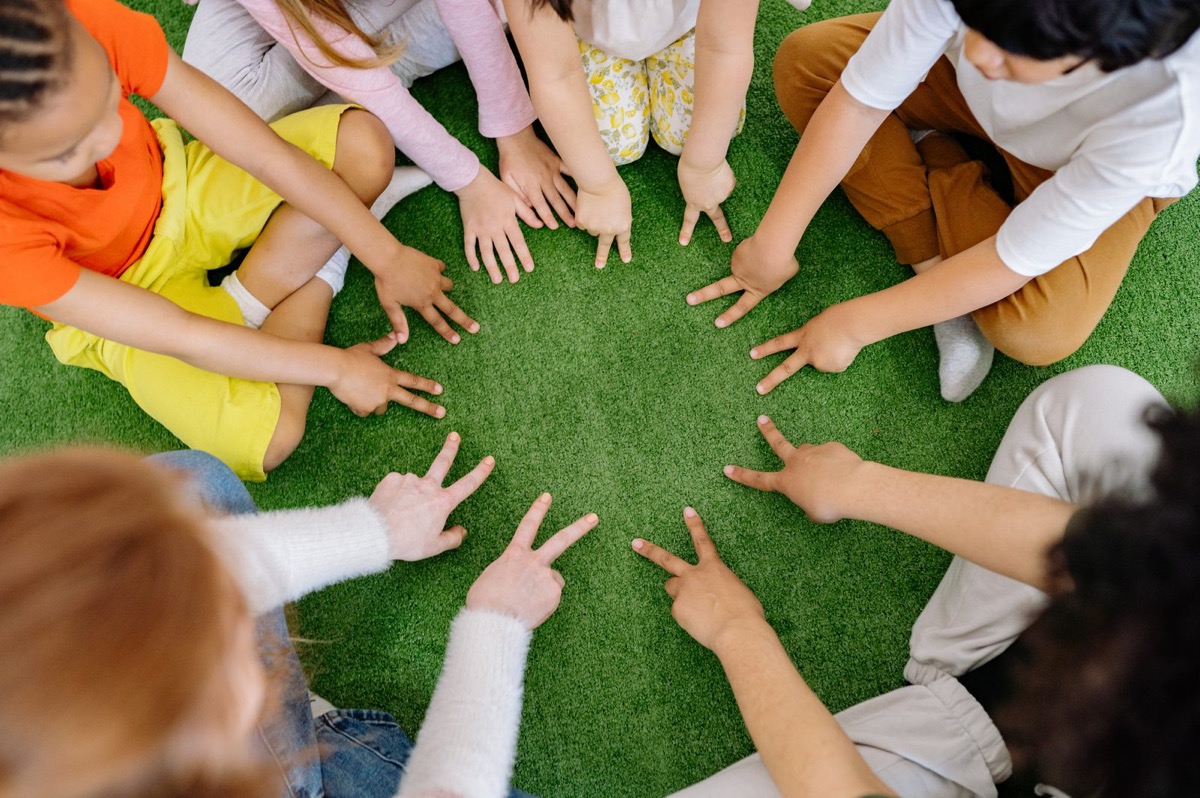 Kids in a circle with hands together on the grass