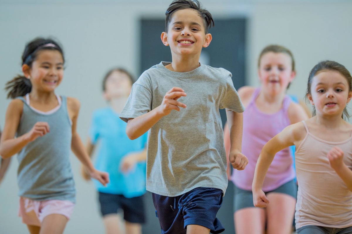 Smiling kids racing across a school gym